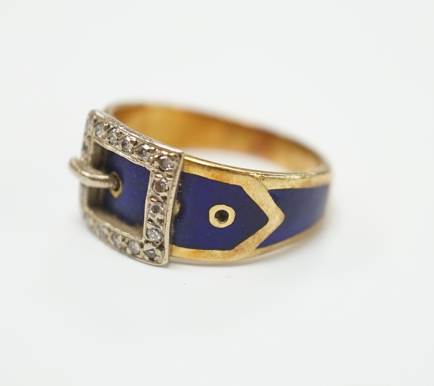 An early 20th century 18ct, diamond chip and blue enamel set buckle ring, size Q, gross weight 8.9 grams.